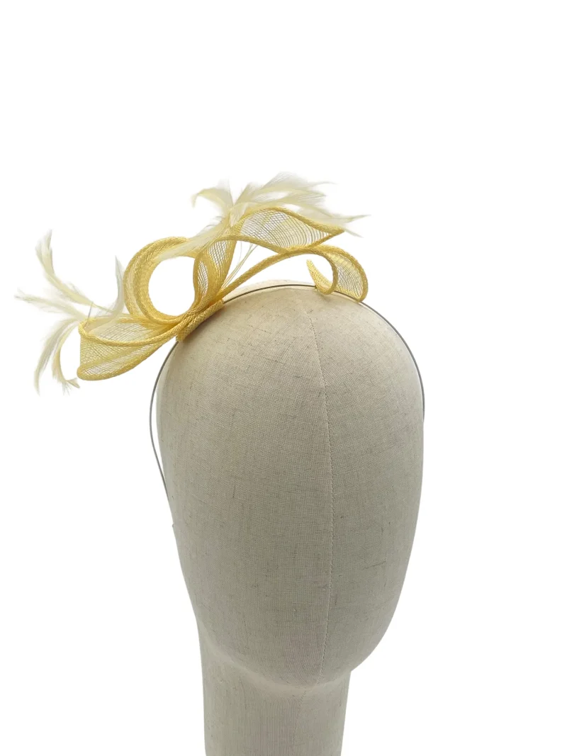Dainty lemon minimalist sculptural fascinator with feather quill detail, angled view on a mannequin head