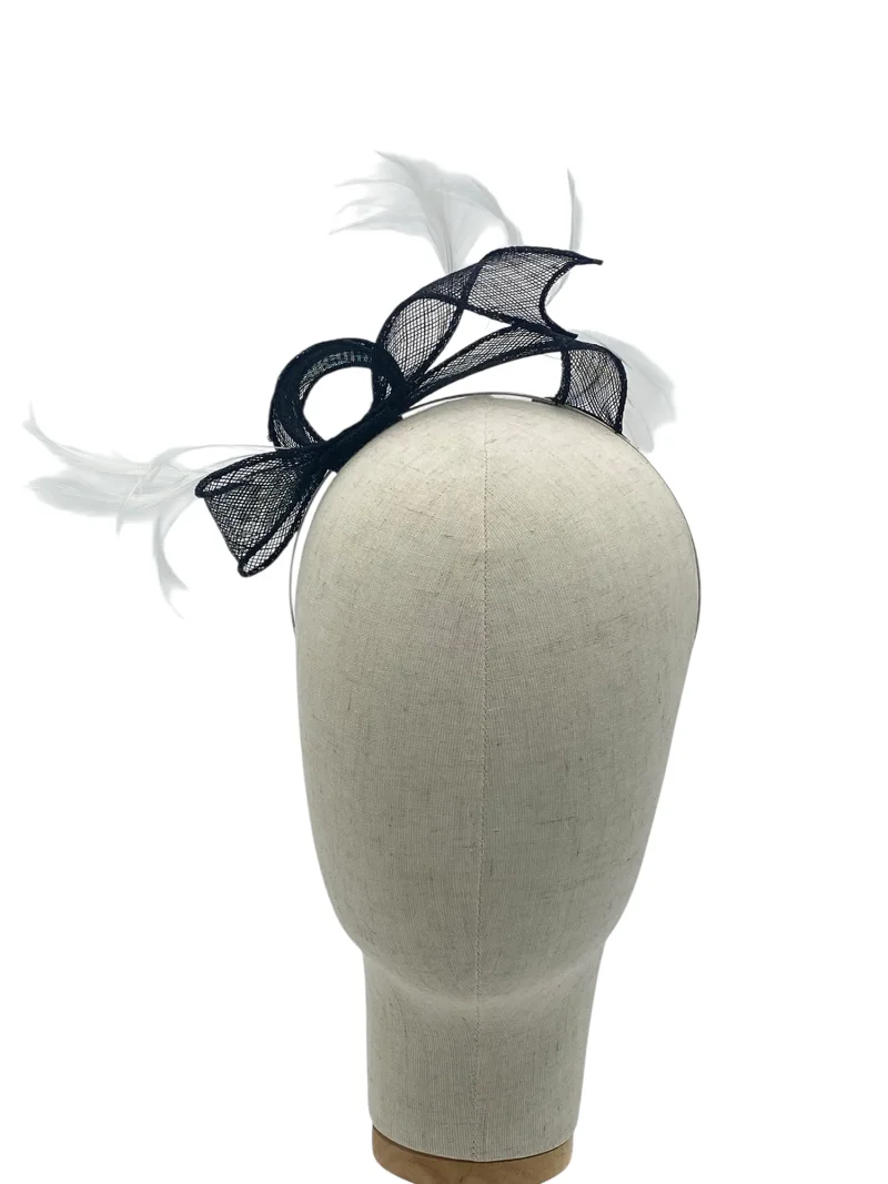 Dainty black and white minimalist sculptural fascinator with twisted sinamay swirl and feather spray, front-angle view on a mannequin head