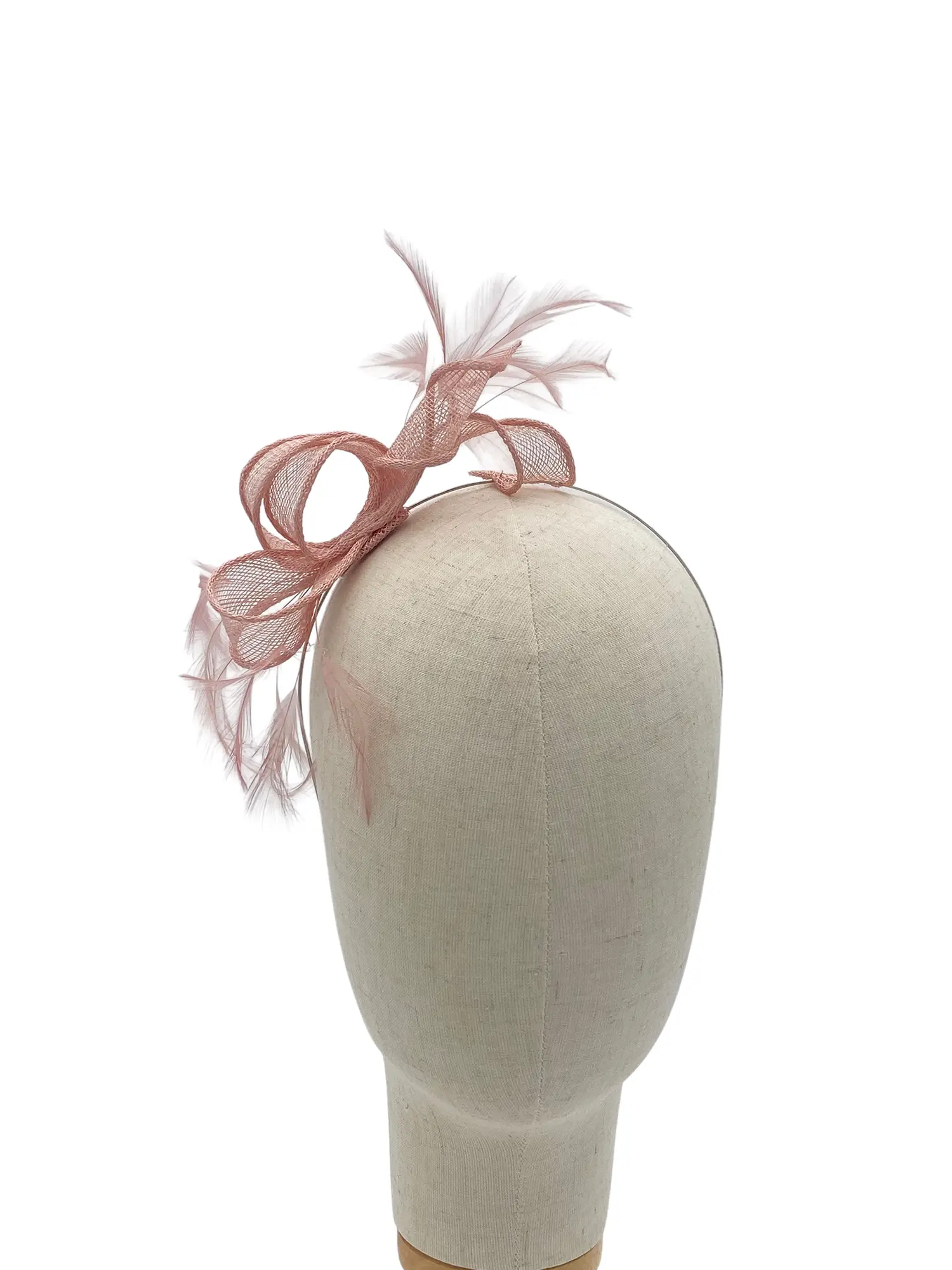 Beige mannequin head wearing a blush pink fascinator with mesh loops, a bow-shaped ribbon, and soft white feathers.
