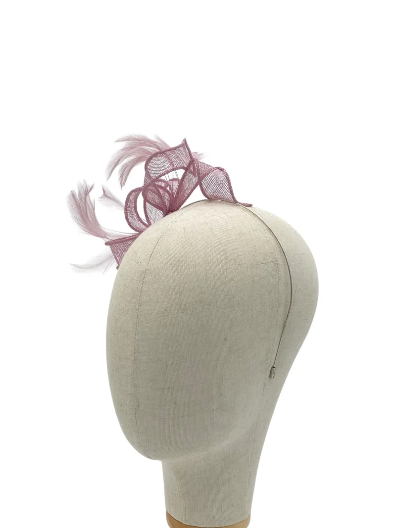 Beige hat on a mannequin featuring a purple mesh fascinator with feathers and swirls.