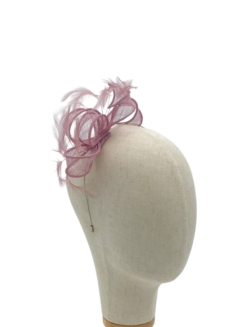 Beige mannequin head wearing a pink mesh feather fascinator attached with a thin comb at the back.