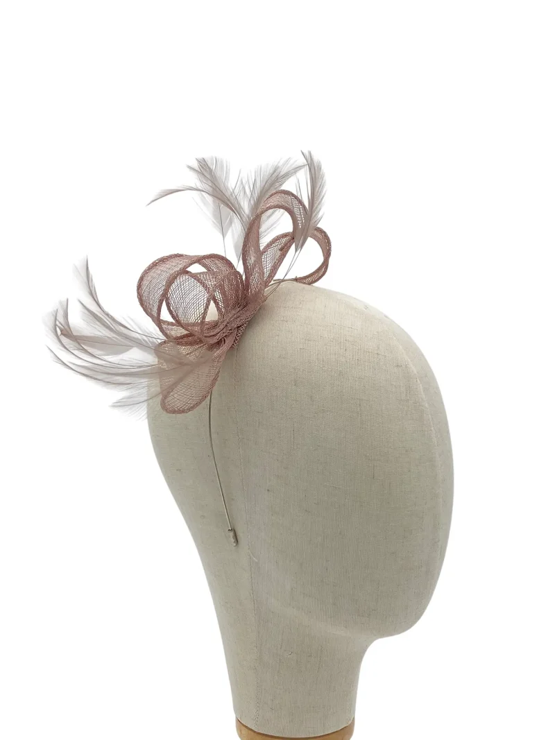 Beige dress form wearing a pink mesh fascinator with feather accents on the side of the head.