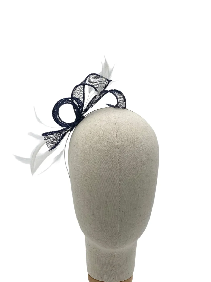 Beige mannequin head wearing a navy fascinator with mesh loops and white feathers.